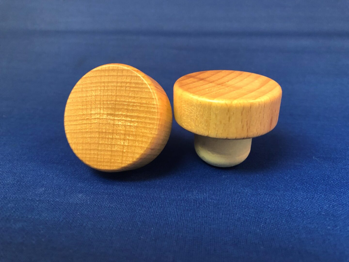 Two Natural Varnished 42x15/24.2 knobs on a blue background.