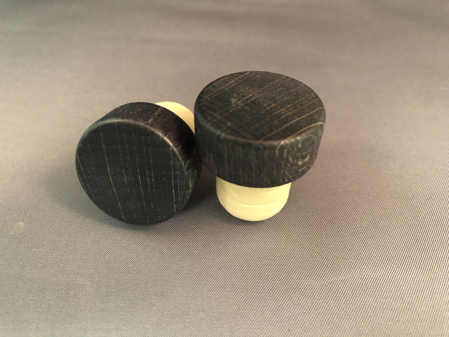 Two Antique Black 29x13/19.5 wine stoppers on a grey surface.