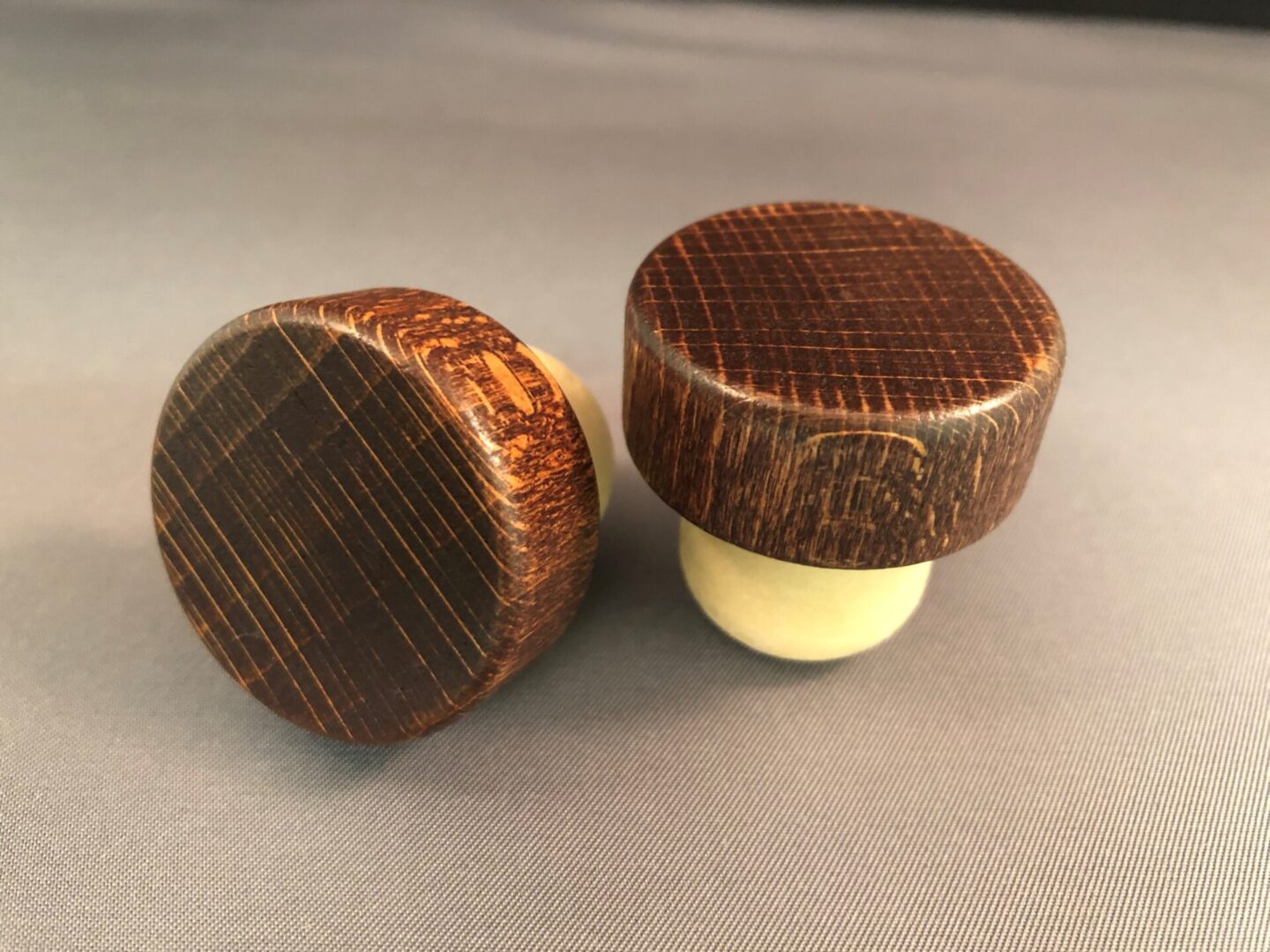 Two Red Mahogany 34x14/22.5 wine stoppers on a grey surface.