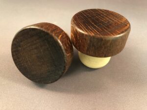 Two Walnut 34x14/22.5 wine stoppers on a grey surface.